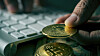 closeup of a young man having a bitcoin from a pile of bitcoins while is using a computer, with a dramatic effect
