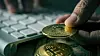 closeup of a young man having a bitcoin from a pile of bitcoins while is using a computer, with a dramatic effect