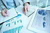 Hands of businesswoman writing down financial data in notepad