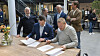Senioringeniør Håkon Eyde Kjuus i Forsvarsmateriell og administrerende direktør Eivind Helgaker i Ice signerer samarbeidsavtale under påsyn av fornøyde medarbeidere fra Ice og Forsvarsmateriell.