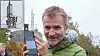 Sjefsarkitekt for mobilnett i Telenor Norge, Petter Aglen, med sin første 5G-mobil med 5G-symbolet på skjermen. Over telefonen ser vi mobilmasta der 5G-utstyret befinner seg. På det lille bildet innfelt øverst til venstre, ser vi at selve 5G-antennene er de nest øverste i masta. Inne i boksen befinner også radioutstyret seg.