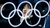 Illustrasjonsbilde: De olympiske ringene reflektert i et glass. En kvinnelig tilskuer sitter bak glasset og ser på mixed double-semifinalen i curling mellom Canada og Norge under de olympiske vinterlekene i Pyeongchang, Sør-Korea.