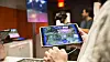 Dette er et kombinert AR/VR-spill fra Accenture. Én spiller har en iPad. Når denne pekes mot et fysisk bord, dukker det opp et landskapskart med ulike mineraler. Denne personen viser en person med VR-briller hvor vedkommende skal forflytte seg for å finne mineraler. Foto: Erlend Tangeraas Lygre