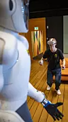 Bernt Børnich har tatt på seg VR-briller og kontrollere for å styre Eve til å bøye seg mot gulvet for å plukke opp ting. Foto: Jan Johannessen