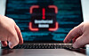 Finger typting on the laptop keyboard, blurred warning sign unauthorized access on the screen, computer crime. Hacker, data, code, encryption, data breach, spyware, communication problems, computer language, security, firewall.
